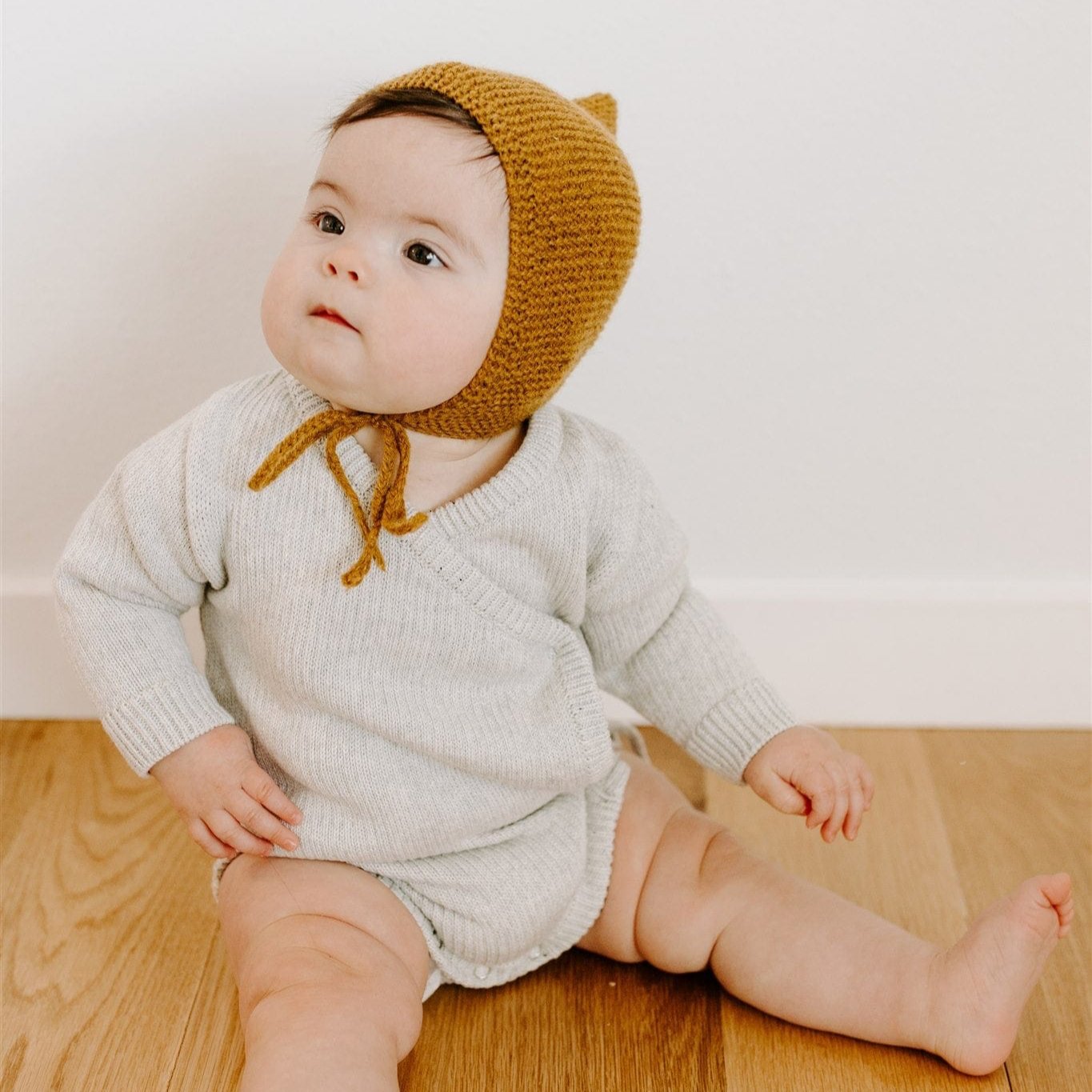 Oaklyn bodysuit in an airy neutral dove gray, featuring a whimsical kimono-style tie closure and snap buttons for easy diaper changes. Soft cotton yarn fabric for baby’s comfort, perfect for winter wardrobes.