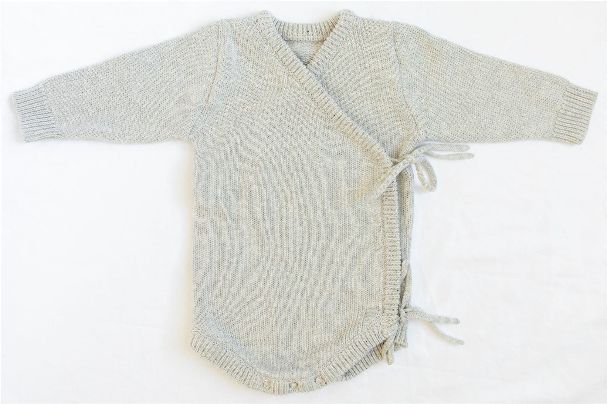 Oaklyn bodysuit in an airy neutral dove gray, featuring a whimsical kimono-style tie closure and snap buttons for easy diaper changes. Soft cotton yarn fabric for baby’s comfort, perfect for winter wardrobes.