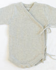 Oaklyn bodysuit in an airy neutral dove gray, featuring a whimsical kimono-style tie closure and snap buttons for easy diaper changes. Soft cotton yarn fabric for baby’s comfort, perfect for winter wardrobes.