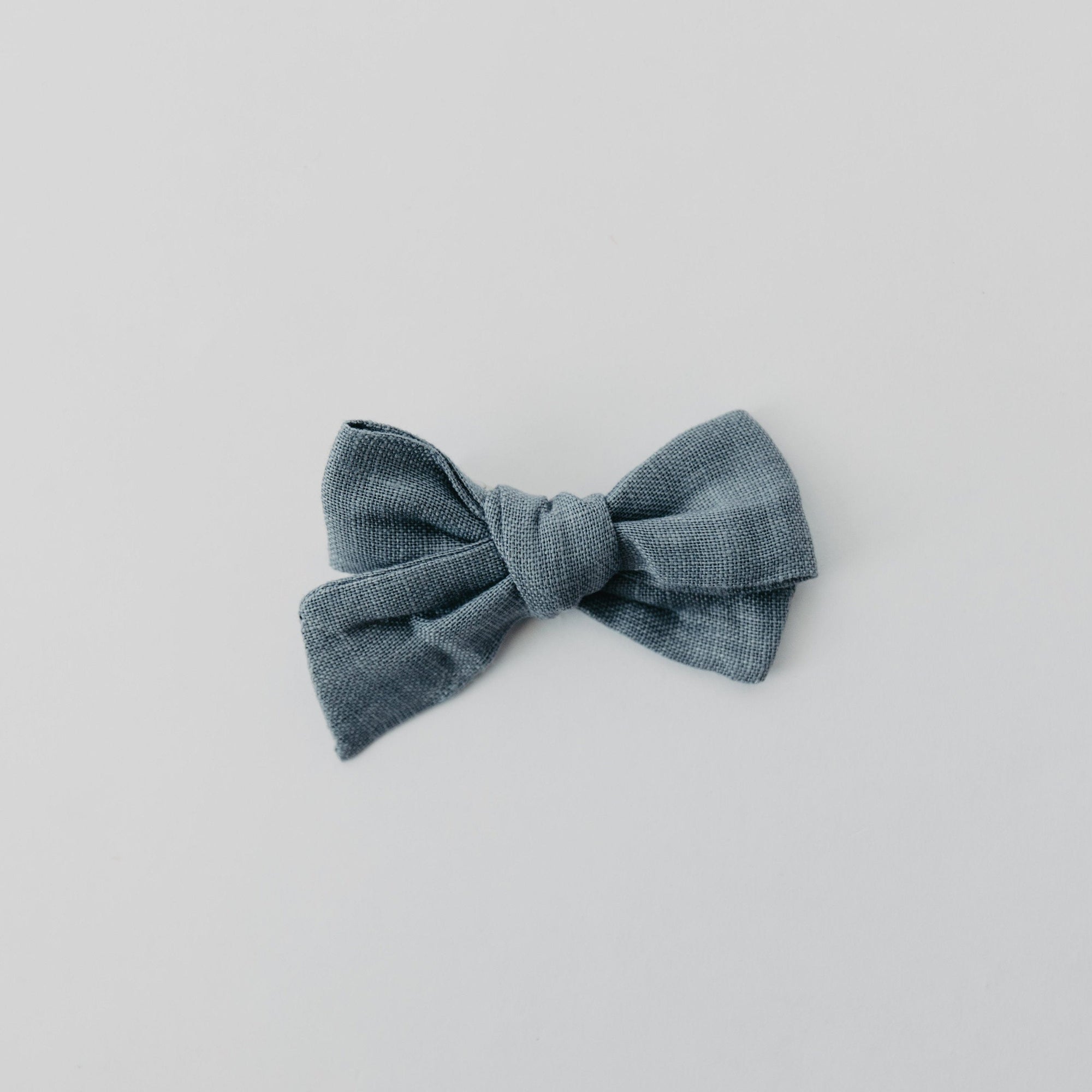 Handmade linen bow in soft clay color, attached to an alligator clip, perfect for adding a stylish touch to any outfit. 