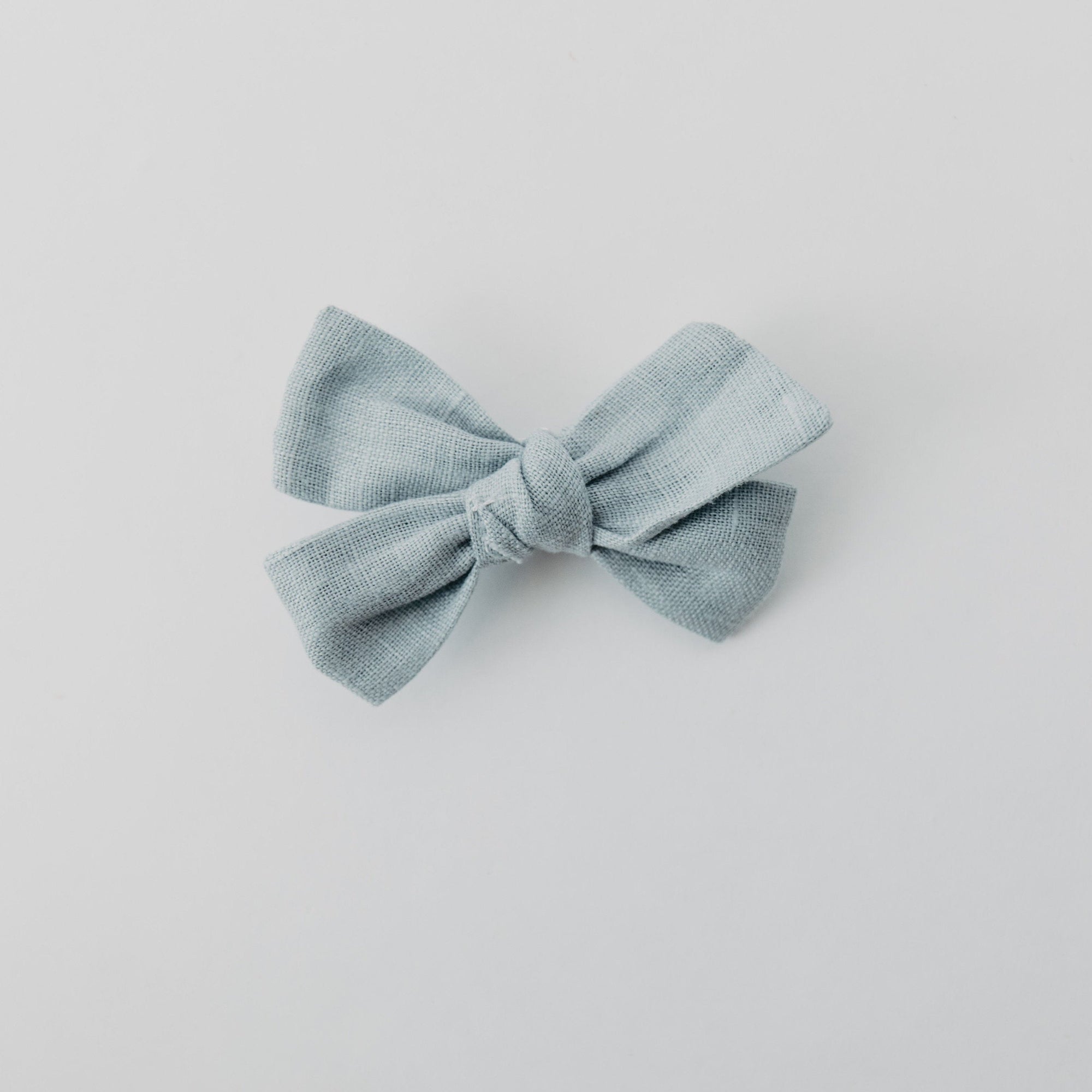 Handmade linen bow in soft clay color, attached to an alligator clip, perfect for adding a stylish touch to any outfit. 