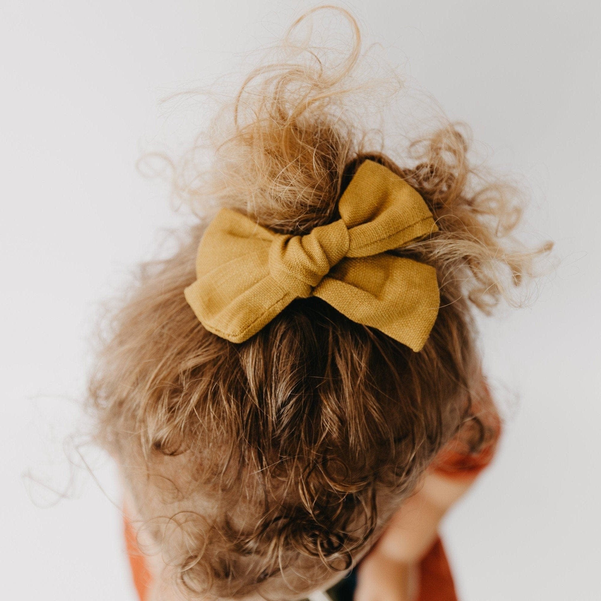 Handmade linen bow in soft clay color, attached to an alligator clip, perfect for adding a stylish touch to any outfit. 