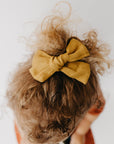 Handmade linen bow in soft clay color, attached to an alligator clip, perfect for adding a stylish touch to any outfit. 