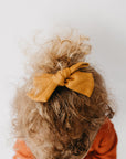 Handmade linen bow in soft clay color, attached to an alligator clip, perfect for adding a stylish touch to any outfit. 