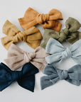 Handmade linen bow in soft clay color, attached to an alligator clip, perfect for adding a stylish touch to any outfit. 