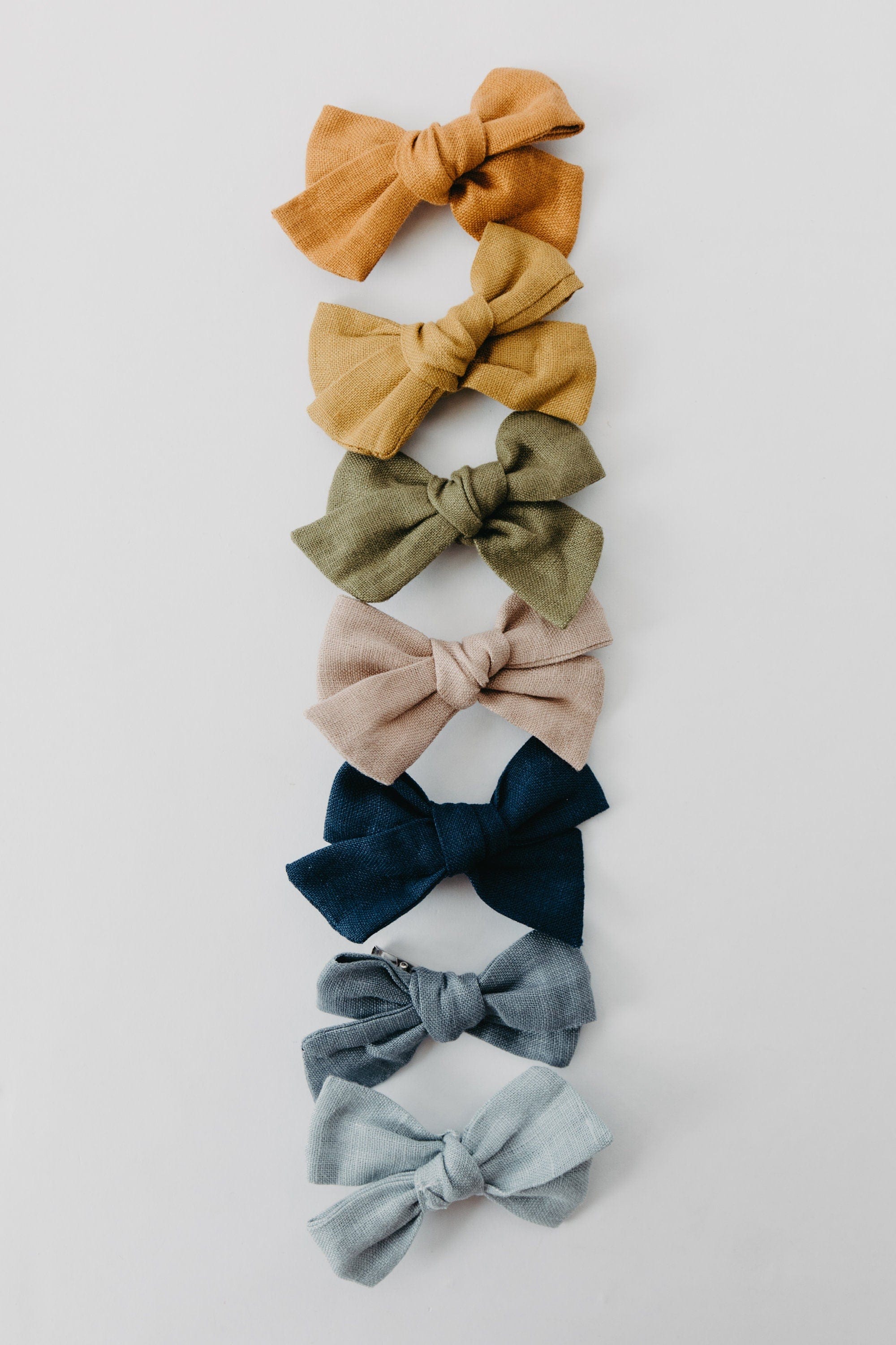 Handmade linen bow in soft clay color, attached to an alligator clip, perfect for adding a stylish touch to any outfit. 