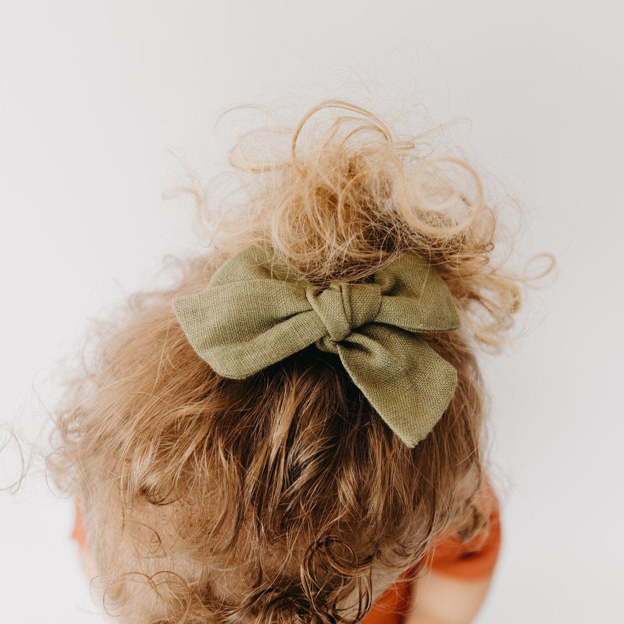 Handmade linen bow in soft clay color, attached to an alligator clip, perfect for adding a stylish touch to any outfit. 