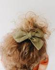 Handmade linen bow in soft clay color, attached to an alligator clip, perfect for adding a stylish touch to any outfit. 