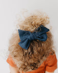 Handmade linen bow in soft clay color, attached to an alligator clip, perfect for adding a stylish touch to any outfit. 